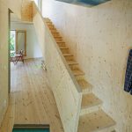 blue painted plywood wall plywood staircase colorful doormat plywood floor round table small chair affordable modern prefab house by Tommy Carlsson