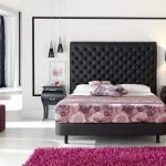 floral patterned bedding idea beneath tall decorative black tufted headboars above white pillows between black nighstand beneath table lamps with purple area rug