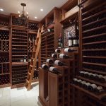 wonderful large wine cellar design in exclusive style with wooden wine racks and straight ladder aside table upon white tile flooring beneath white ceiiling