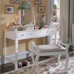a settee furniture a console table with drawers and decorative mirror beautiful classic table lamp with green cap beautiful carpet with floral patterns some wall decorations