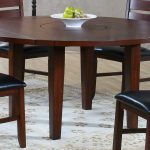 round wooden drop leaf dining table for small spaces with black and wooden chairs plus modern rug in floral motif plus wooden floor and fresh fruits