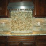 stunning natural tone groutless backsplash design with mosaic small tiles beneath woden cbainetry with marble countertop