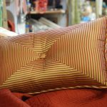 A throw pillow with gold and red strips motif for its cover