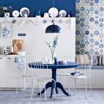 Simple but elegant kitchen set and dining furniture  in dark blue theme some dishware collections organized at permanent shelf and hung on the wall beautiful blue pendant lamp