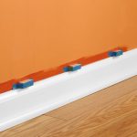 Pure white baseboard with bright orange wall paint wood planks floors