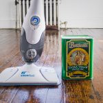 simple designed steam cleaning for wooden floor with adjustment setting and cleaning liquid in green package and dark wooden floor