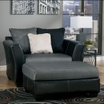 Black leather oversized recliner furniture with white pillow and an table ottoman