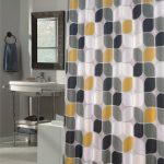Mid century modern shower curtain with three tone colors for the pattern a small bathroom vanity with  sink and faucet a  framed mirror grey wool bathroom mat