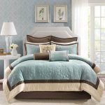 Queen bed furniture with white headboard and teal brown bedding and pillows white round bedside table small white vase for decorative plant