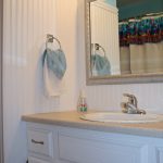 white small bathroom idea with white beadboard and wall mirror and sink and towel hanger and storage