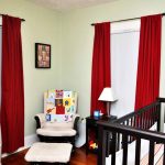 red blackout curtains nursery with large wooden baby crib and comfy white armchairs with stool and wooden nightstand with table lamp