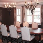 Seven White Upholstered Dining Chairs With Big Wooden Table And Double Rustic Chandelier