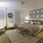 elegant apartment bedroom design with creamy bedding and white sofa with tufted patterna  and wooden floor and patterned rug