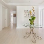 lovable hallway interior design with round glass table with indoor plant and laminated wooden floor and glass door