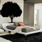 lovable white and gray bedroom design with orange accent pillow and tree wallpaper and black rug