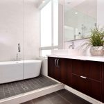 luxurious modern bath design with marroon cabinet and white top and walk in shower and white bathtub and small tile flooring