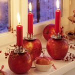 Unique and creative candle centerpiece for table which is made by putting small and lower profile candlestick holder over red apples