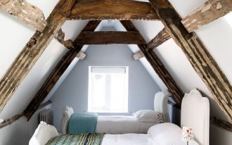 small attic bedroom for twin kids classic styled twin beds in white turquoise rug exposed wood ceiling beams white wall and floor