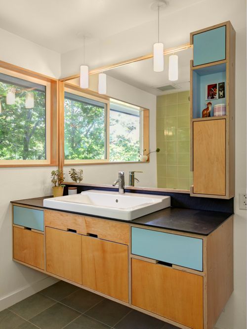 floating light wood bathroom vanity with black countertop undermount sink in white wood cabinets and blue painted drawers extra wood framed mirror