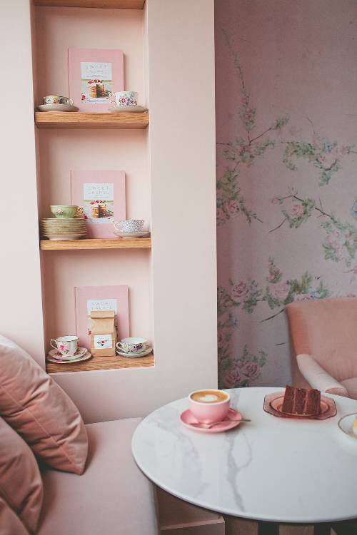 decorative vintage tea cups recessed racks marble top coffee table floral wallpaper in soft pink walls