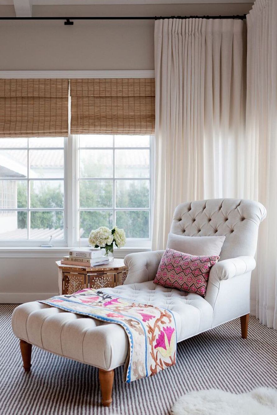 large reading corner lounge chaise with white tufted upholstery cheerful pattern throw blanket and pillows Moroccan wood side table striped & textured area rug white window curtains