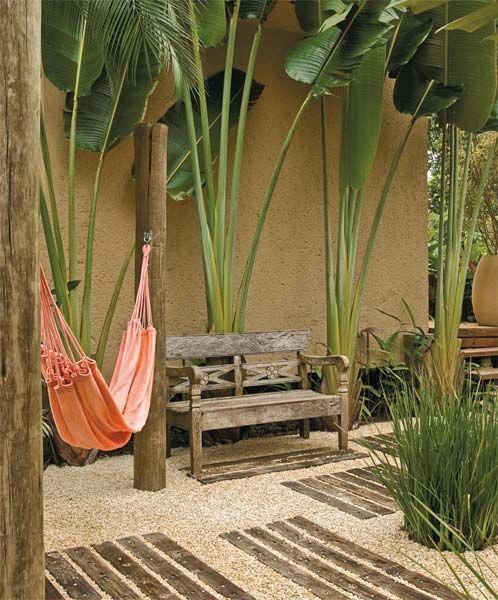 tropical outdoor space idea linen hammock in pastel some huge tropical plants shabby wood bench seat with back