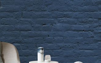 deep blue brick walls white round top side tables with cage like base light gray accent chair with gray knitted blanket