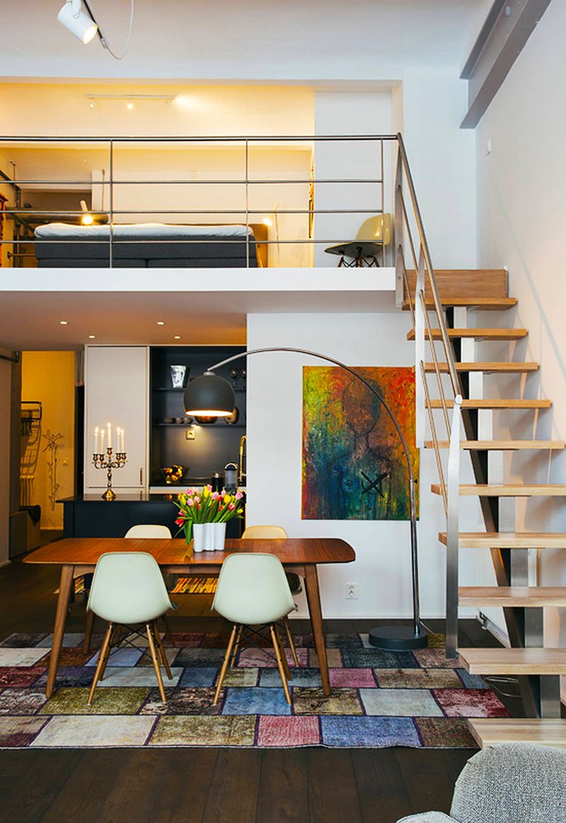 contemporary loft design with natural wood staircase with metal railing system Scandinavian style dining furniture colorful modern area rug
