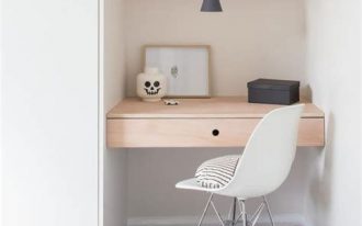 small minimalist home office with light wood working desk tiny white working chair with hairpin legs upper wood shelving unit gray floors