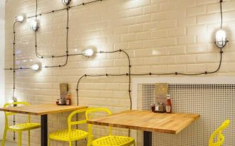 minimalist industrial coffee shop interior with white subway tile walls with stunning modern industrial lighting installations wood top tables yellow chairs