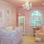 cute pink baby nursery room with iron white crib and gorgoeus chandelier also amazing flower patern sofa feat white framed window and large carpeting