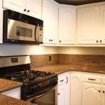 rubbed bronze kitchen appliances such as gas stove unit and oven brown granite kitchen countertop and white kitchen cabinetry