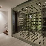 adorable large wine cellar design on glass transparent idea aside white wall and wooden brown staircase with flashing orange pallete on the wall