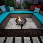 beautiful turquoise banquette design with blue gray and red cushions on concrete patio idea with round in ground fire pit