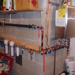 indoor tankless water heater installation on brick walls with metal pipes and woods