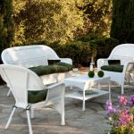 luxurious white lwan chair idea with semi round curve backrest and armrest with bold green bolster for seating before white multishelves coffee table upon stone patio aside lush vegetation
