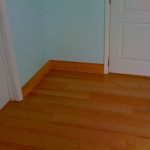 yellowish wooden floor design with light blue wall design and white doors and brown laminated baseboard