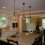 traditional kitchen remodeling northern va with white wooden kitchen cabinets and kitchen island with granite countertop and wooden chairs plus pendant lamp