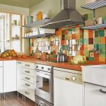Beautiful backsplash in multicolors orange kitchen counter white painted cabinets electric stove metal floating shelves for organizing cooking tools and dishware collections