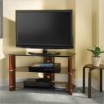 Corner angled TV console with open shelves underneath a small round table some media players