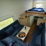 Elevated bed with staircase and storage system U shape sofas in dark blue color scheme and a white coffee table for mobile houses