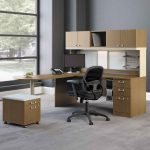 beige modular office computer desk with black swivel chair in grey office design with glass window