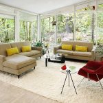 red womb chair reproduction in living room with round glass end table and shag rug plus cozy brown sofa and yellow cushion and curved glass coffee table