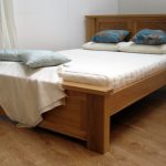 Simple modern wood bed frame with headboard white bedding white pillows and blue throw pillows