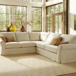 White L shape with brown throw pillows textured white area rug glass windows with wood trims