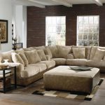 luxurious industrial living room design with white couch and loveseat set with rectangle coffee table on patterned area rug with wooden small end table with brick wall and exposed beam