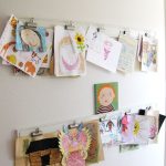 white wall with pictures and painting and paper clip for displaying kids art