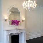 Classic white framed mirror over classic mantled fireplace in white beautiful white pendant lamp a pair of small white wall lamps