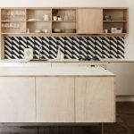 Monochromotic wallpaper for backsplash in simple and small kitchen  unfinished wall mounted wooden open shelves for displaying dishware collection  a kitchen island with white top