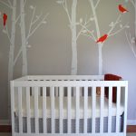 White Baby Crib With Pretty Wallpaper And Grey Carpet On Floor